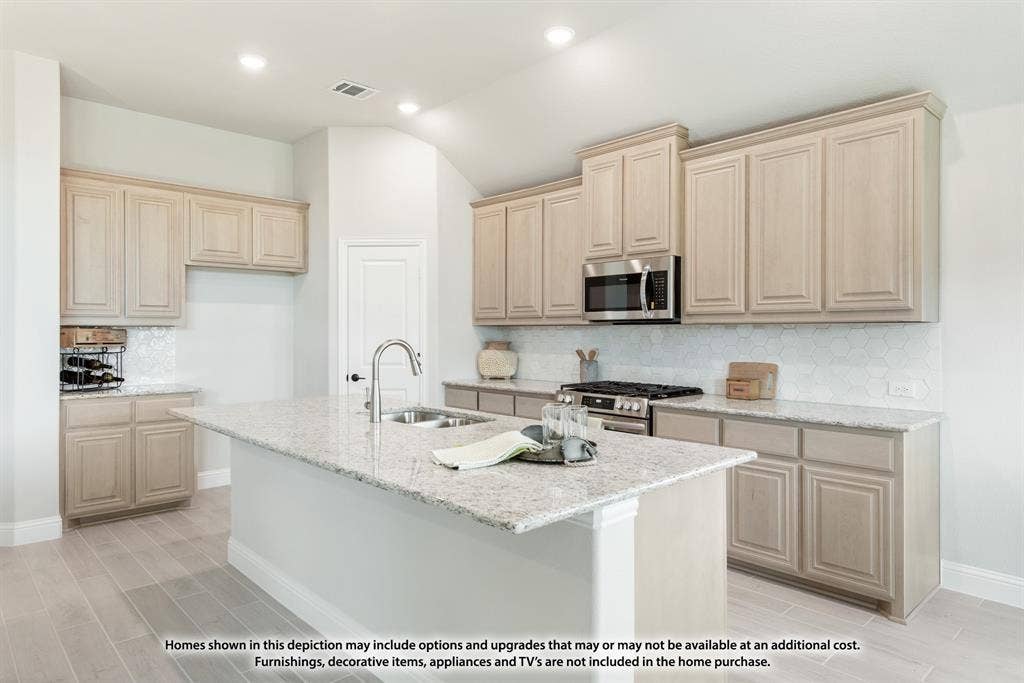 942 Cardinal Drive, Midlothian, TX 76065 Kitchen featuring a central island with a sink, light-toned cabinetry, light-colored countertops, a tile backsplash, and wood-finish flooring