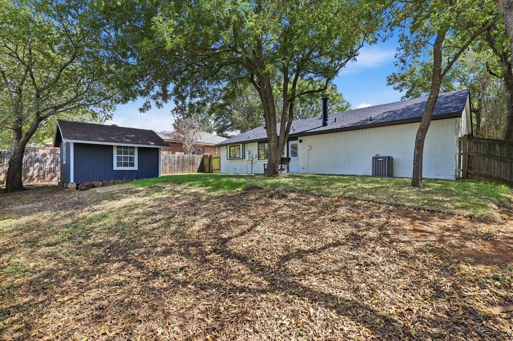 3405 Mill Ridge, Bedford, TX 76021 Expansive backyard featuring a detached storage shed, mature trees, and a private wooden fence