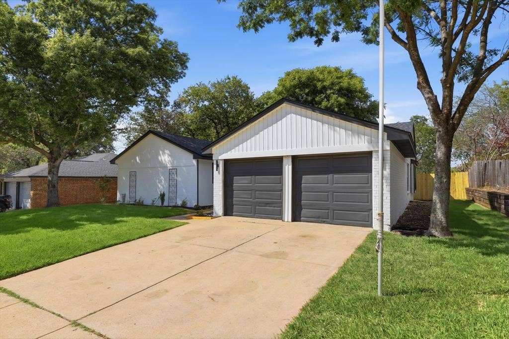 3405 Mill Ridge, Bedford, TX 76021 Two-car garage with dark paneled doors, light vertical siding, and a dark shingle roof