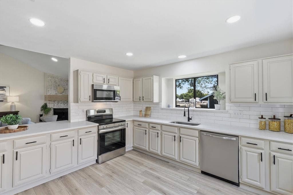 3405 Mill Ridge, Bedford, TX 76021 White shaker cabinetry, light wood-finish flooring, stainless steel appliances, recessed lighting, and a subway tile backsplash