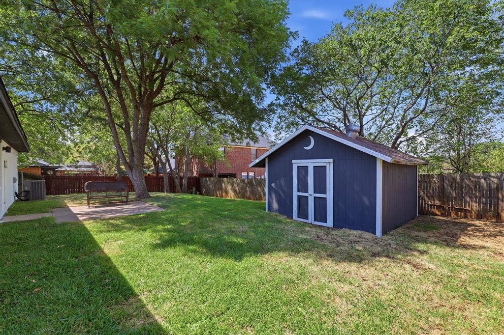 3405 Mill Ridge, Bedford, TX 76021 Expansive backyard with a manicured lawn, established trees, and a detached storage shed