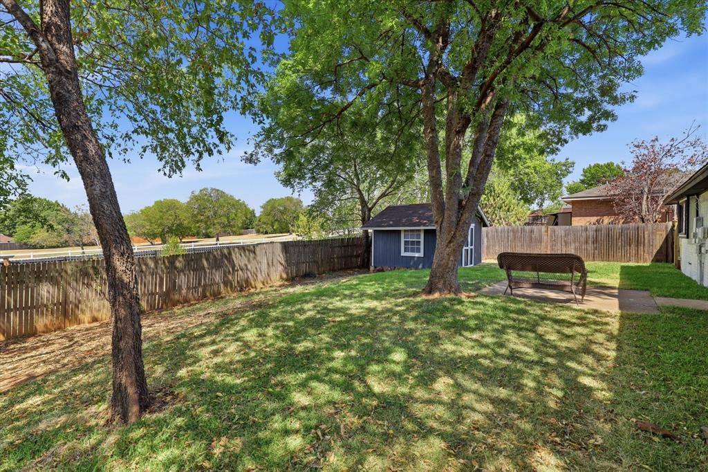 3405 Mill Ridge, Bedford, TX 76021 Expansive backyard oasis featuring mature shade trees, manicured lawn, and wooden privacy fencing