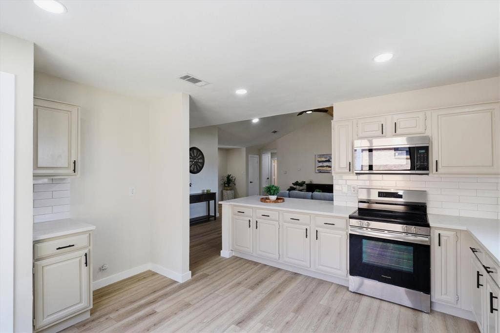 3405 Mill Ridge, Bedford, TX 76021 Modern kitchen featuring light wood-finish flooring, white cabinetry with black hardware, white subway tile backsplash, and recessed lighting