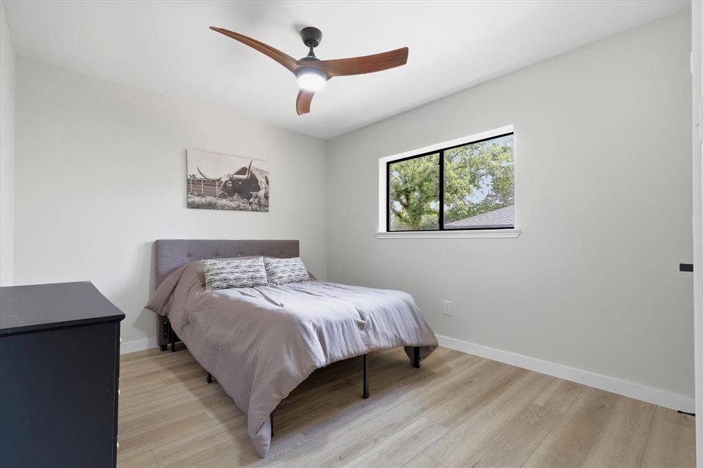 3405 Mill Ridge, Bedford, TX 76021 Light wood-finish flooring with crisp white baseboards, a modern ceiling fan with integrated lighting, and a window with black trim