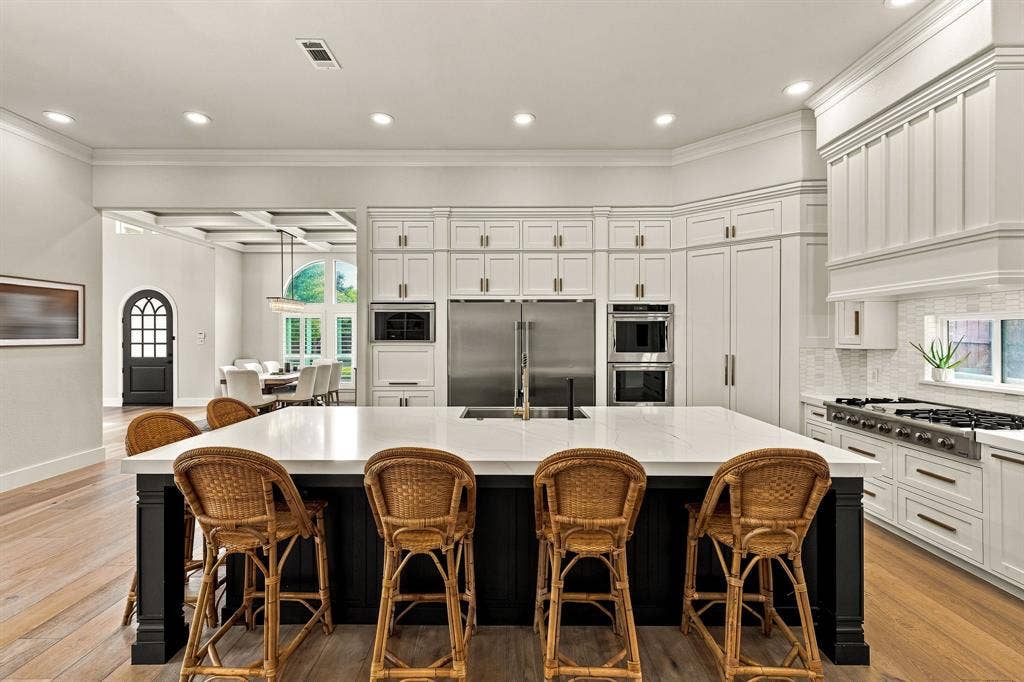 5941 Tiburon Drive, Plano, TX 75093 Gourmet kitchen with a large central island, white cabinetry, integrated stainless steel appliances, and wood-finish flooring