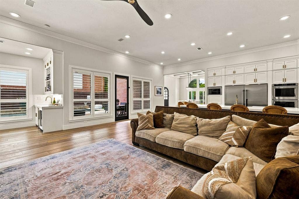 5941 Tiburon Drive, Plano, TX 75093 Open-concept living area featuring wood-finish flooring, a wet bar with under-cabinet refrigeration, a kitchen with stainless steel appliances, and white cabinetry