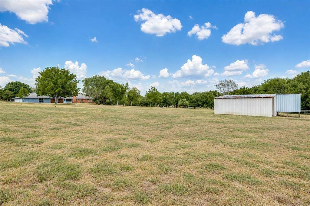 2406 County Road 852, McKinney, TX 75071 Expansive grassy area featuring a white metal outbuilding and mature trees