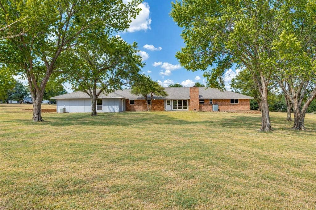 2406 County Road 852, McKinney, TX 75071 Expansive green space featuring mature trees and a brick and siding exterior