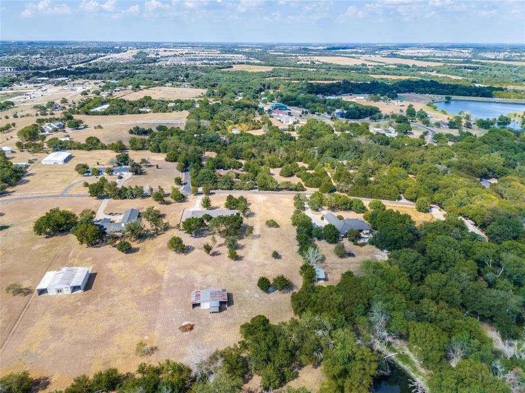 2406 County Road 852, McKinney, TX 75071 Expansive property featuring multiple structures, mature trees, and a distant body of water