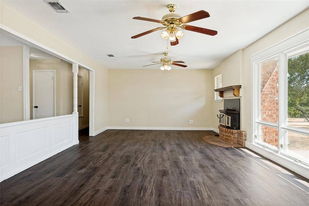 2406 County Road 852, McKinney, TX 75071 Wood-finish flooring, multiple ceiling fans with integrated lighting, brick fireplace surround with a wood mantel, and large picture windows