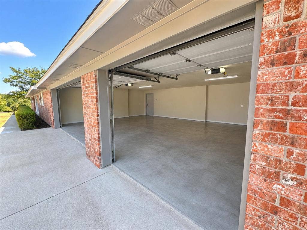 2406 County Road 852, McKinney, TX 75071 Spacious multi-car garage with brick exterior, concrete flooring, and overhead lighting