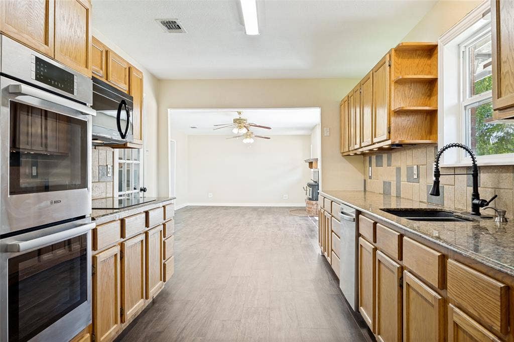 2406 County Road 852, McKinney, TX 75071 Kitchen featuring wood cabinetry, integrated double ovens, a contemporary black faucet, and stone countertops