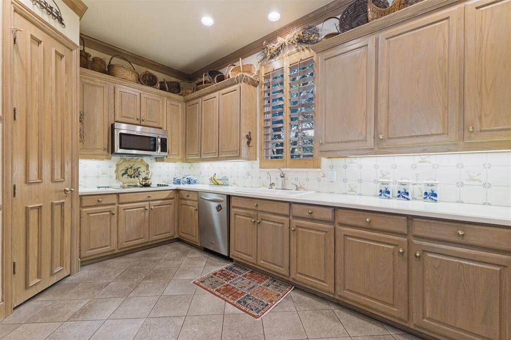12012 Excelsior Way, Dallas, TX 75230 Kitchen featuring wood-finish cabinetry, stainless steel microwave, stainless steel dishwasher, white countertops, and tiled flooring