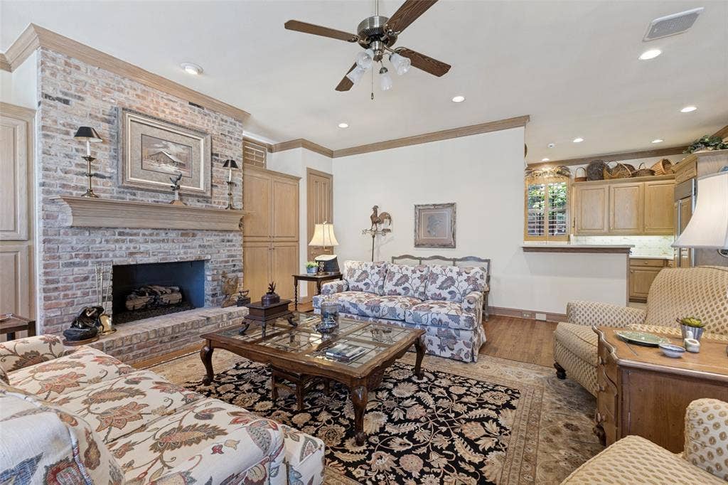 12012 Excelsior Way, Dallas, TX 75230 Brick fireplace with a wood mantle, built-in cabinetry, wood-finish flooring, and recessed lighting