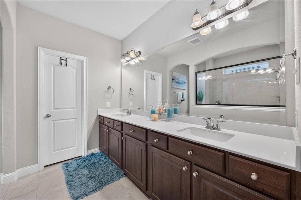 8712 Mccutchins Drive, McKinney, TX 75070 Double vanity with white countertops, dark wood-finish cabinetry, and chrome fixtures