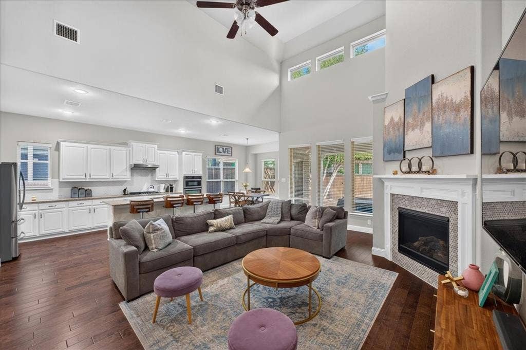 8712 Mccutchins Drive, McKinney, TX 75070 Vaulted ceiling with a ceiling fan, wood-finish flooring, white cabinetry, integrated oven, and a tiled fireplace