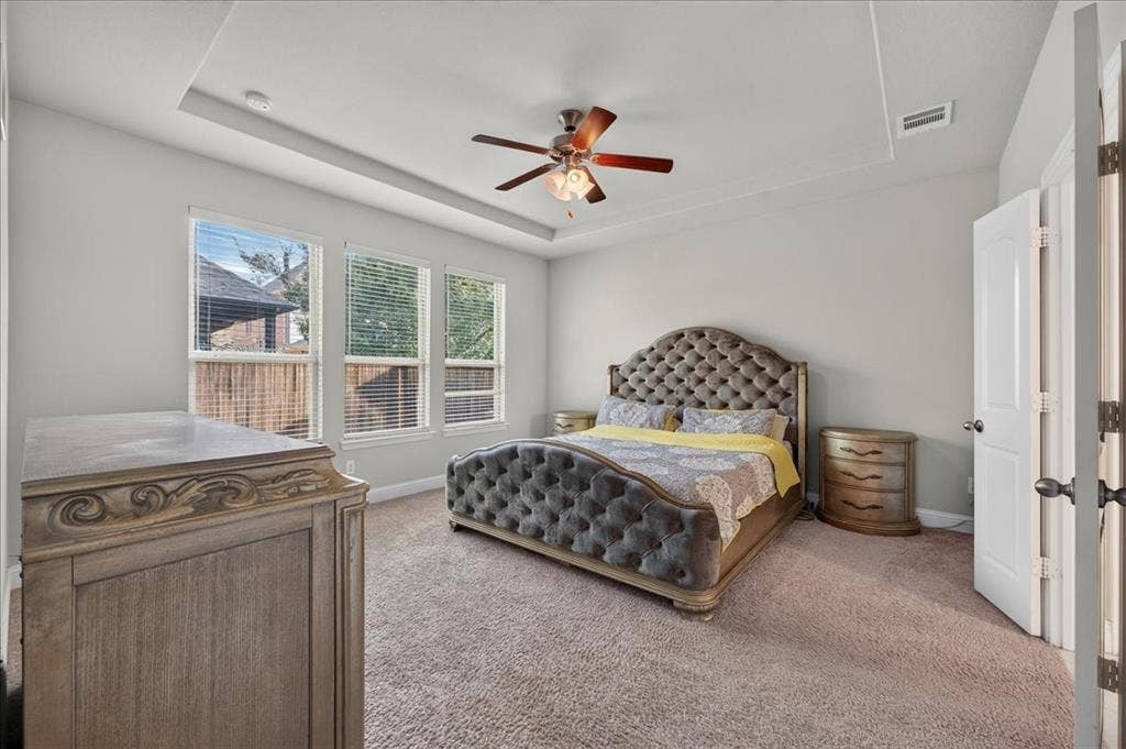 8712 Mccutchins Drive, McKinney, TX 75070 Recessed tray ceiling with a ceiling fan, three windows with blinds, and neutral wall paint