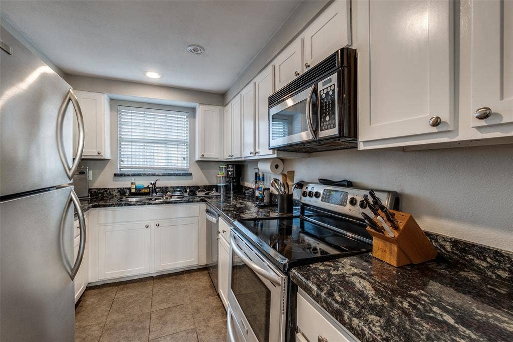 3100 Cole Avenue, #213, Dallas, TX 75204 Kitchen featuring stainless steel appliances, dark stone countertops, white cabinets, and recessed lighting