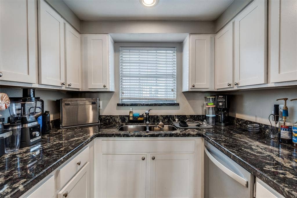 3100 Cole Avenue, #213, Dallas, TX 75204 Kitchen with dark stone countertops, white cabinets, and dishwasher