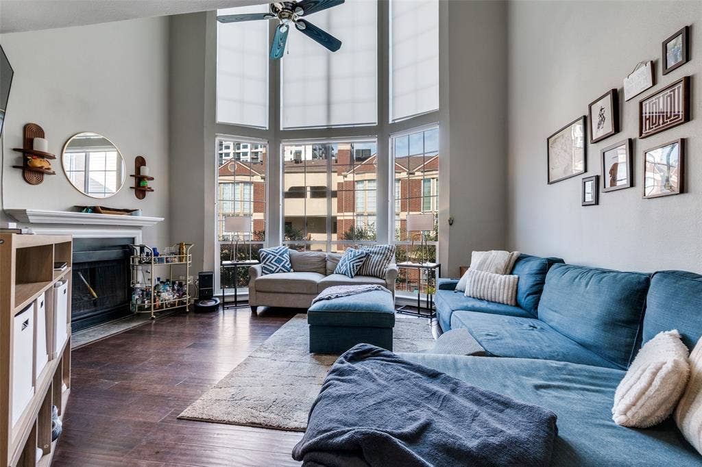3100 Cole Avenue, #213, Dallas, TX 75204 Living area featuring a towering ceiling, dark wood-style floors, a fireplace with flush hearth, and ceiling fan
