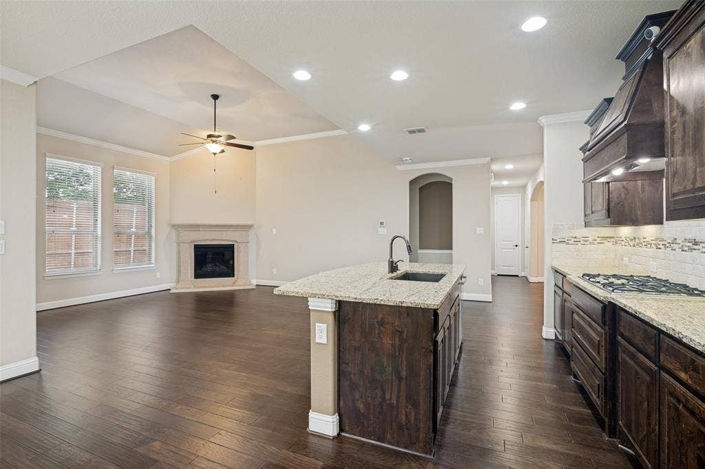 10002 Edgeway Circle, Rowlett, TX 75089 Living area and kitchen as seen from breakfast area. Gas log fireplace with cast stone surround in background.