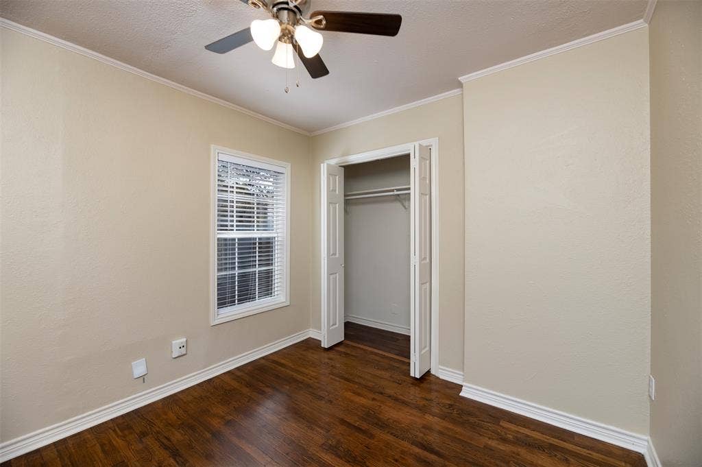 8823 San Benito Way, Dallas, TX 75218 Hardwood-finish flooring, ceiling fan with integrated lighting, white trim and crown molding, and a built-in closet with bi-fold doors