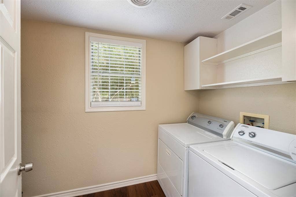 8823 San Benito Way, Dallas, TX 75218 Laundry area featuring a window with blinds, white upper cabinetry, and wood-finish flooring