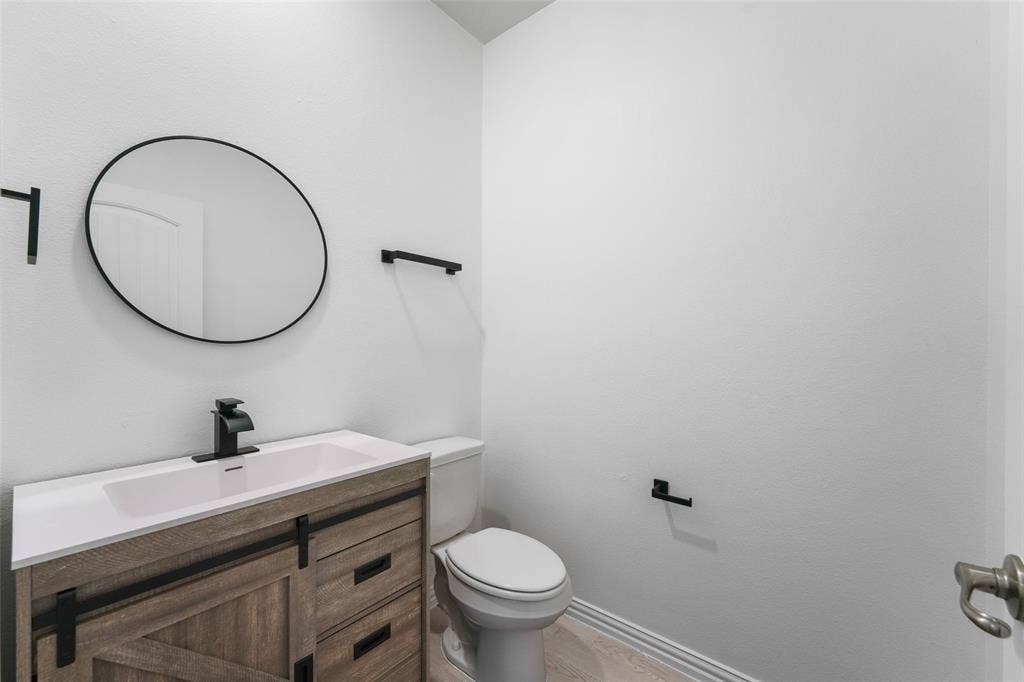 4651 Raleigh Dalton Road, Dallas, TX 75227 Modern vanity with a white integrated sink, matte black faucet, and round mirror