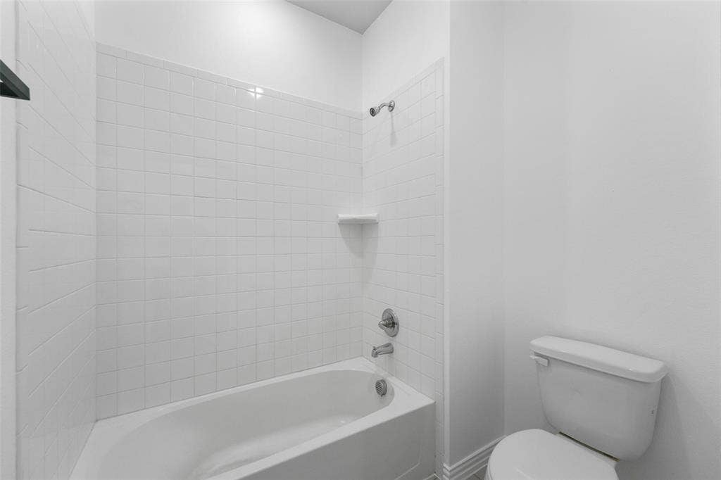 4651 Raleigh Dalton Road, Dallas, TX 75227 White tiled shower with built-in soap dish, chrome fixtures, and a white porcelain bathtub