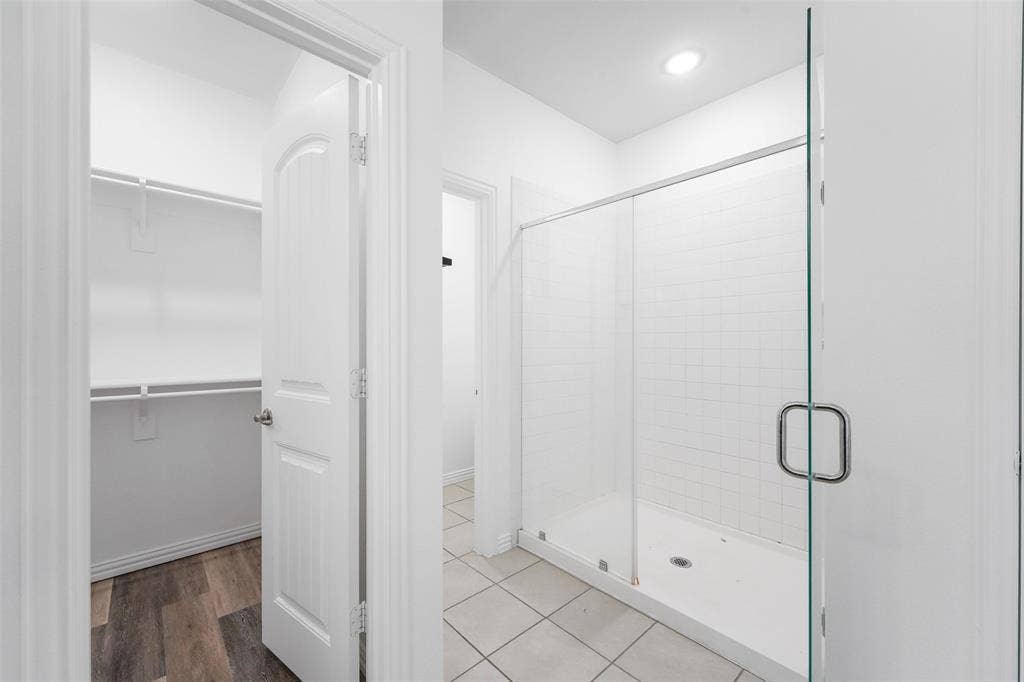 4651 Raleigh Dalton Road, Dallas, TX 75227 Primary Bathroom Featuring Frameless Glass Shower Enclosure with Chrome Hardware, Ceramic Tile Flooring, Recessed Ceiling Lighting, and Clean White Subway Tile Shower Surround with Built-In Shelf