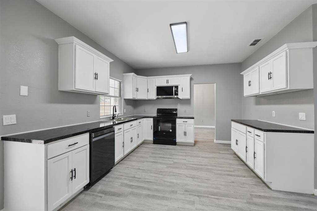 6833 Lyndale Drive, Watauga, TX 76148 Kitchen featuring black range with electric cooktop, light wood-style floors, dishwashing machine, stainless steel microwave, and white cabinetry