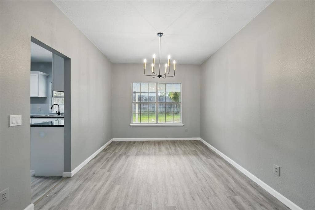 6833 Lyndale Drive, Watauga, TX 76148 Unfurnished dining area featuring a chandelier and light wood finished floors