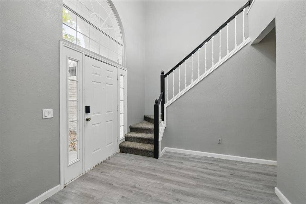 6833 Lyndale Drive, Watauga, TX 76148 Entrance foyer featuring stairs, wood finished floors, and a towering ceiling