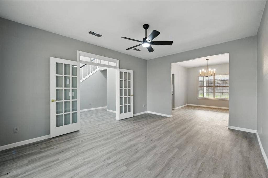 6833 Lyndale Drive, Watauga, TX 76148 Unfurnished room featuring french doors, a chandelier, wood finished floors, and ceiling fan