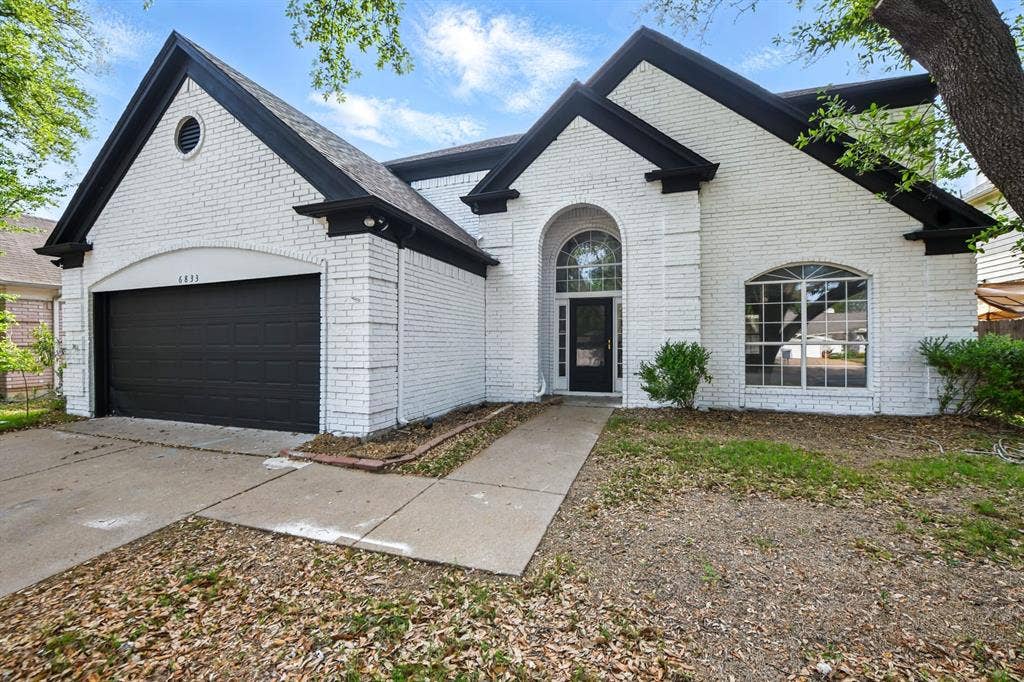6833 Lyndale Drive, Watauga, TX 76148 French country home featuring brick siding, a garage, and driveway