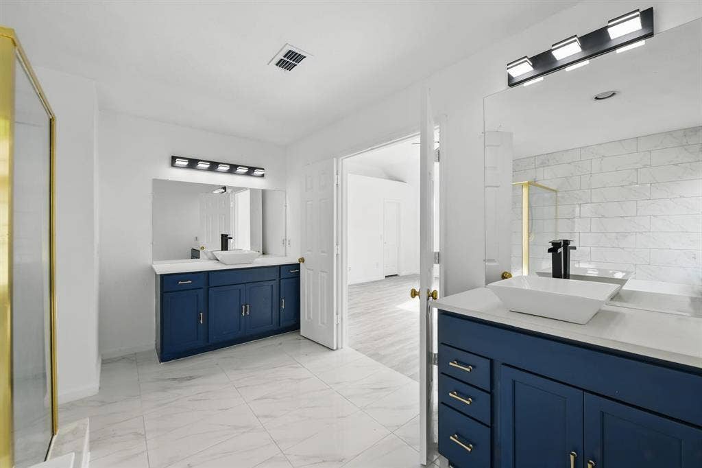 6833 Lyndale Drive, Watauga, TX 76148 Bathroom featuring two vanities, marble finish floors, and a walk in shower