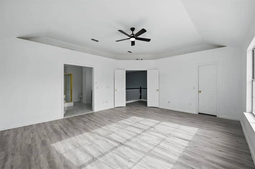6833 Lyndale Drive, Watauga, TX 76148 Unfurnished bedroom featuring wood finished floors, a raised ceiling, and connected bathroom