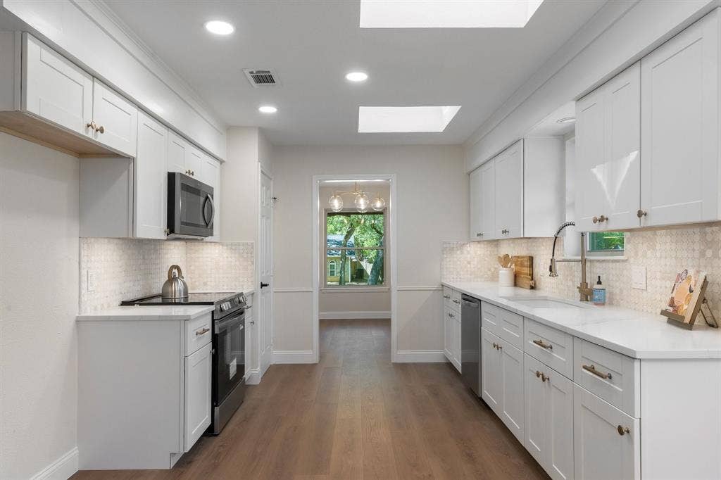 2844 Hurstview Drive, Hurst, TX 76054 Galley kitchen featuring new white shaker cabinetry, new stainless steel appliances, recessed lighting, and a skylight