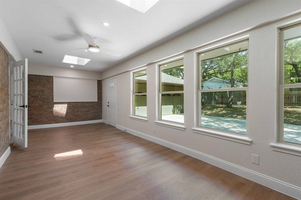 2844 Hurstview Drive, Hurst, TX 76054 Wood-finish flooring, multiple windows, skylights, ceiling fan, and exposed brick-finish wall