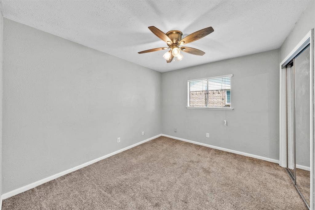 1715 Cherokee Trail, Plano, TX 75023 Wall-to-wall carpeting, window with horizontal blinds, built-in ceiling fan with integrated lighting, and mirrored sliding closet doors