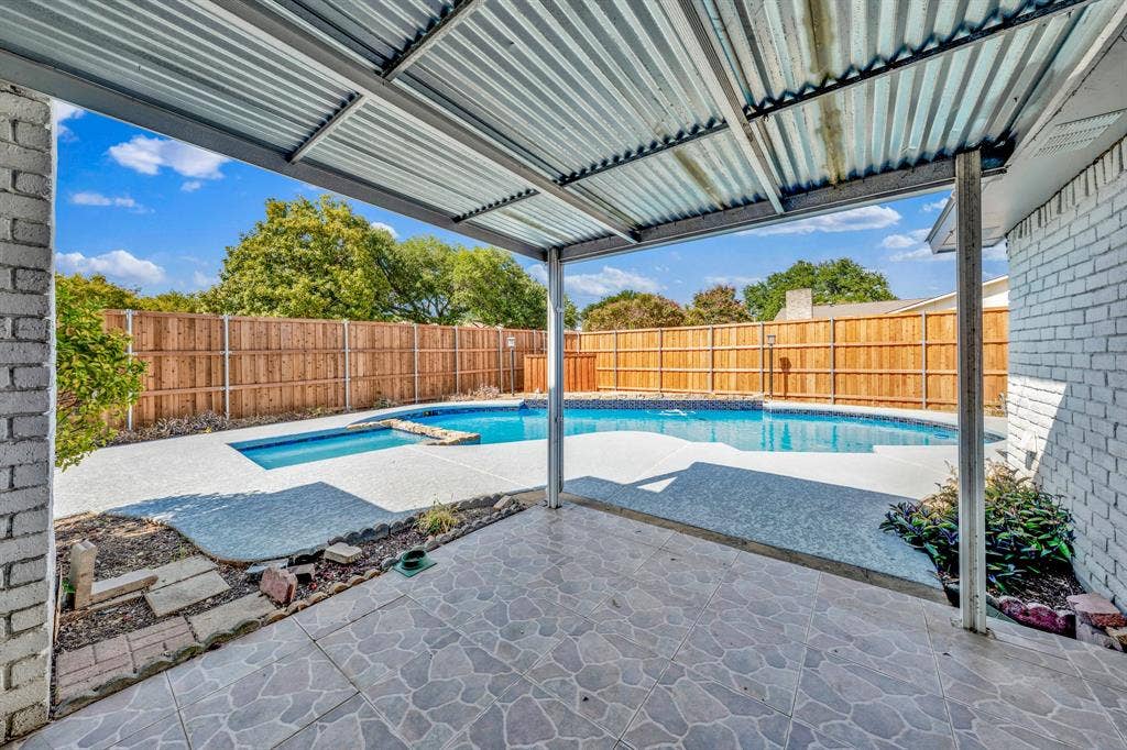 1715 Cherokee Trail, Plano, TX 75023 Covered patio with a tiled surface and corrugated metal roof, overlooking a backyard swimming pool