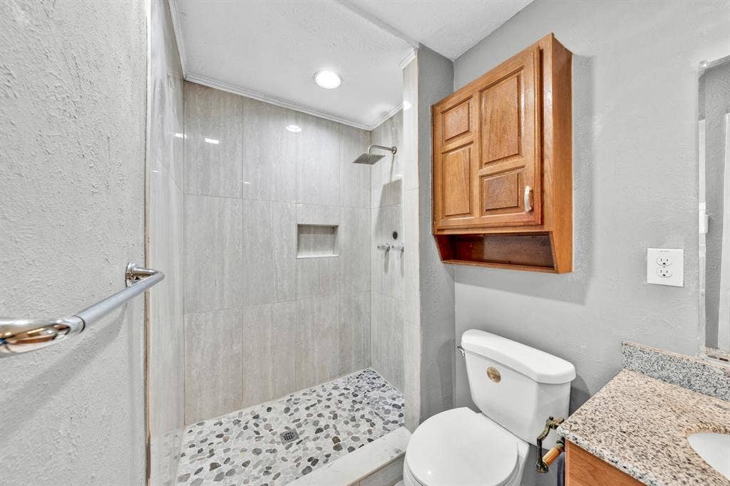 1715 Cherokee Trail, Plano, TX 75023 Walk-in shower with stone tile flooring, recessed niche, and overhead rain shower