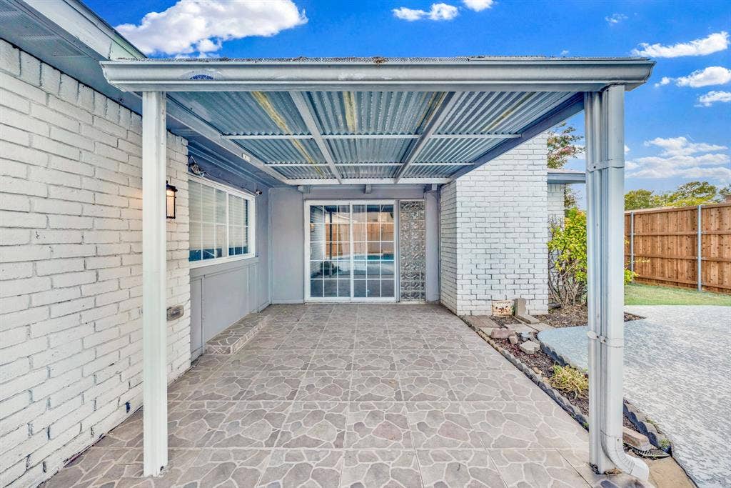 1715 Cherokee Trail, Plano, TX 75023 Covered patio featuring a corrugated metal roof, patterned tile flooring, and white painted brick exterior walls