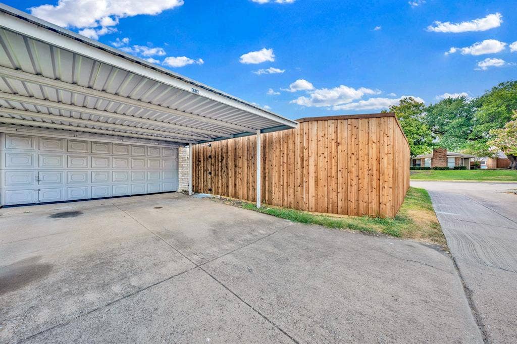 1715 Cherokee Trail, Plano, TX 75023 Attached carport with a corrugated metal roof, a two-car garage door, and a concrete driveway