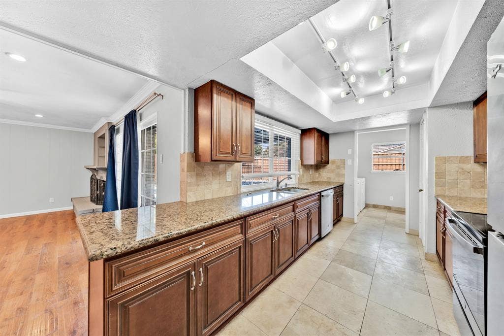 1715 Cherokee Trail, Plano, TX 75023 Kitchen featuring wood cabinetry, light-toned tile flooring, granite countertops, and track lighting