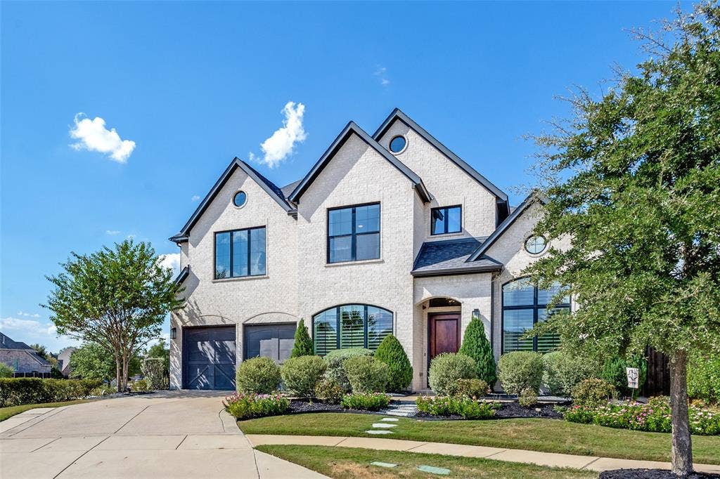 15018 Crape Myrtle Road, Frisco, TX 75035 Stone exterior with black-framed windows, a dark wood entry door, and a two-car garage with dark wood-finish doors