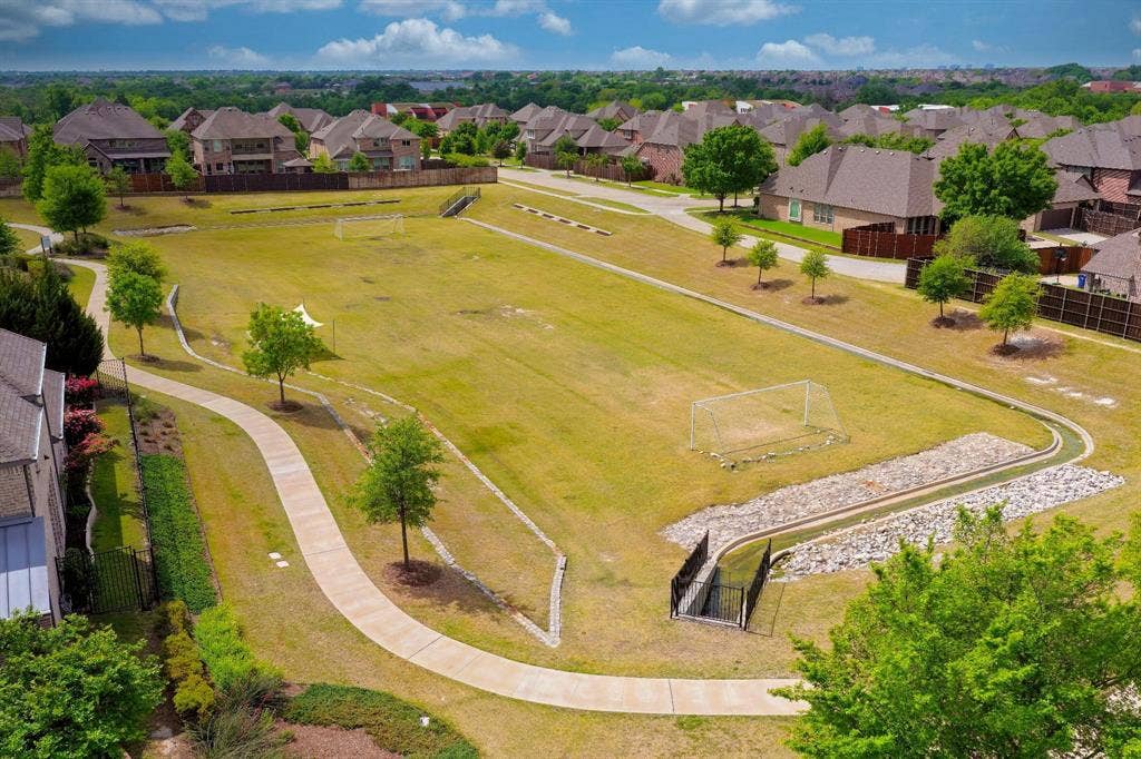 15018 Crape Myrtle Road, Frisco, TX 75035 Expansive green space featuring a paved walking path, mature trees, and a rock-lined water feature
