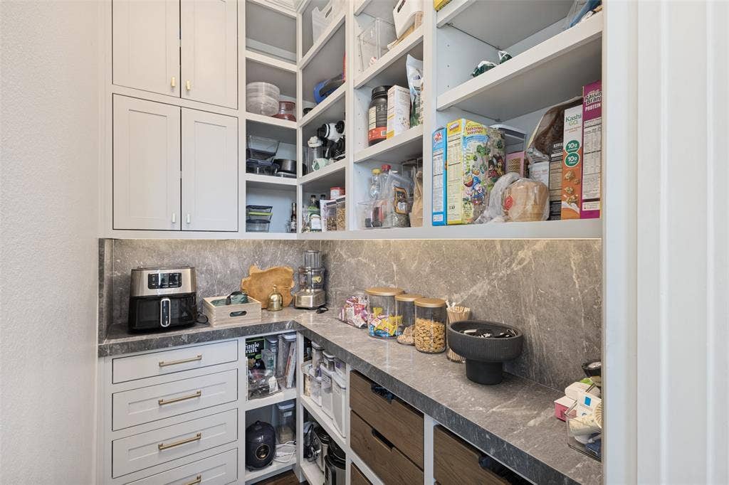 15018 Crape Myrtle Road, Frisco, TX 75035 Custom pantry featuring extensive shelving, built-in cabinetry, durable countertops, integrated drawers, and a fluted wall panel