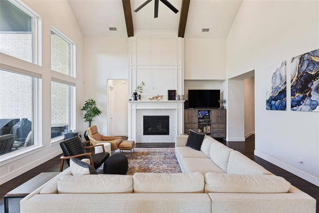 15018 Crape Myrtle Road, Frisco, TX 75035 Vaulted ceiling with exposed wood beams, large windows, fireplace with tile surround, and dark wood-finish flooring