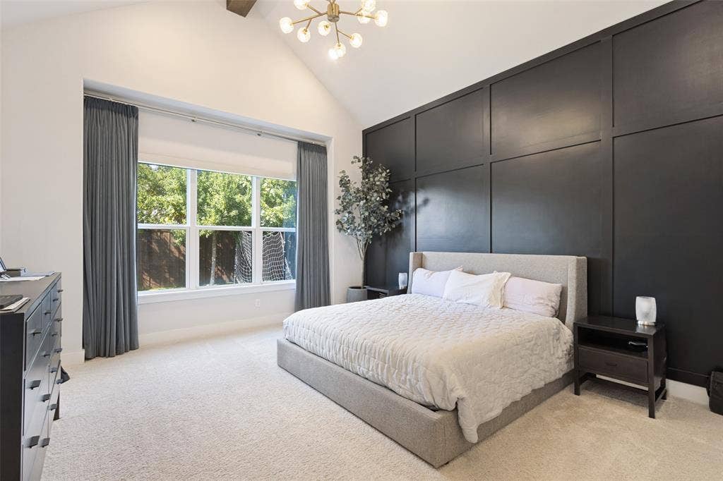15018 Crape Myrtle Road, Frisco, TX 75035 Vaulted ceiling with an attached light fixture, a large window with privacy shades, a dark paneled accent wall, and light-colored carpeting